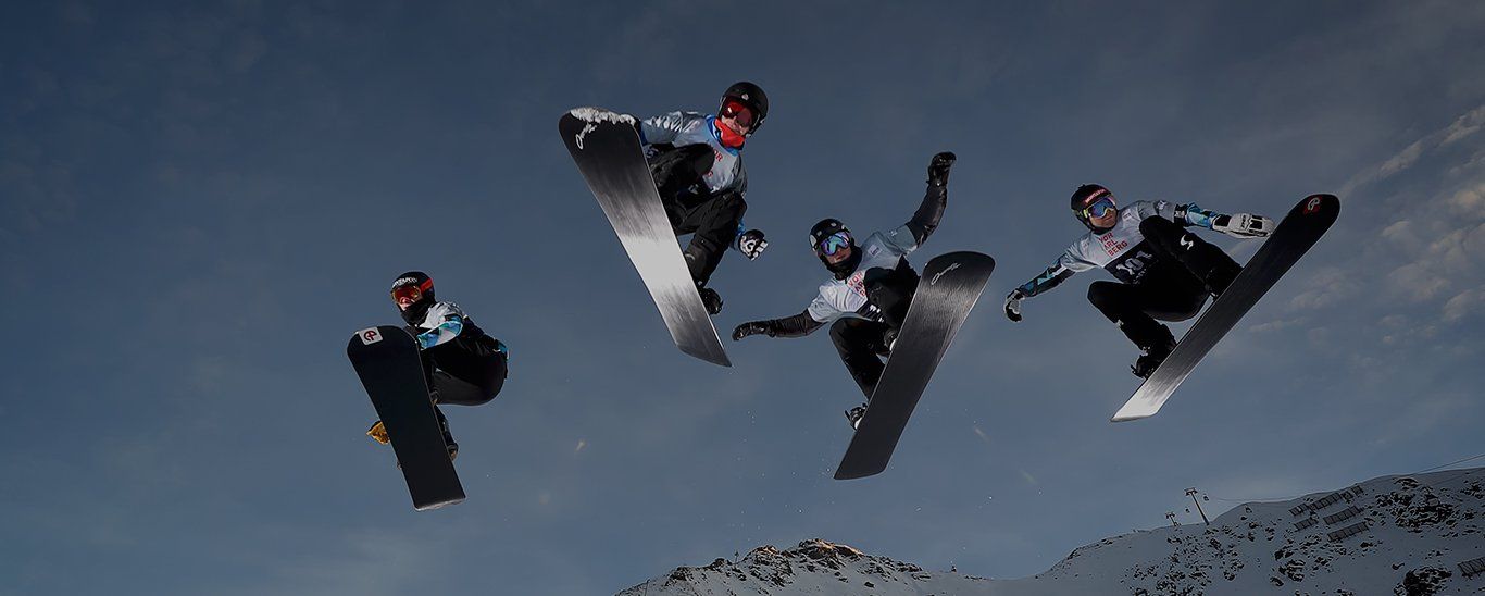 Four people leap through the air on snowboards.